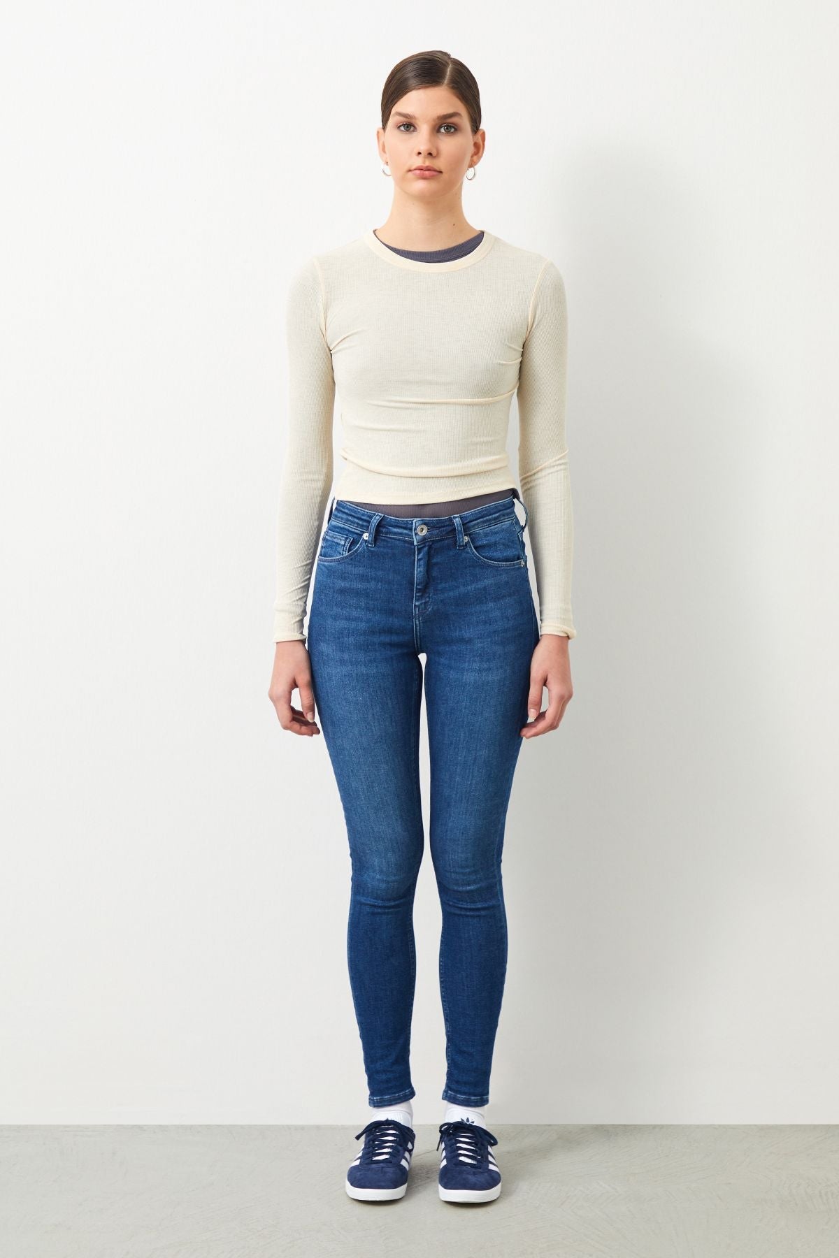 Model wearing Sira Skinny Fit Dark Blue Women's Jeans with a tight white top, highlighting the perfect fit.