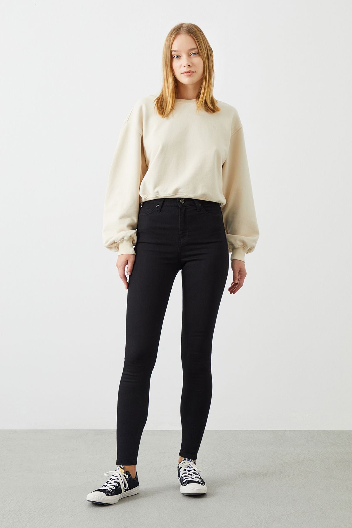 Stylish outfit featuring black slim jeans from sustainable brand RA Denim paired with an off-white organic cotton sweater.