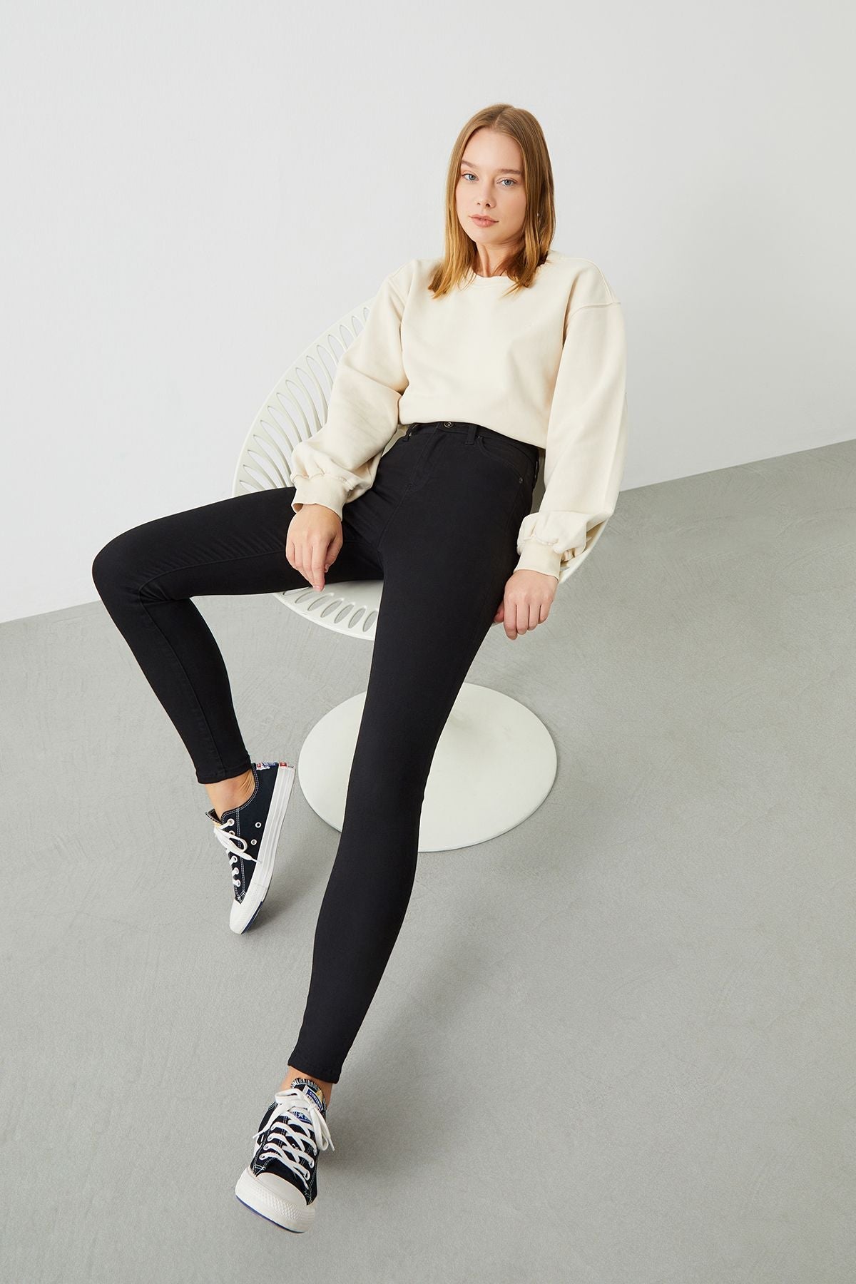A woman wearing the sustainable Black Slim Jeans, emphasizing their flattering super skinny fit.