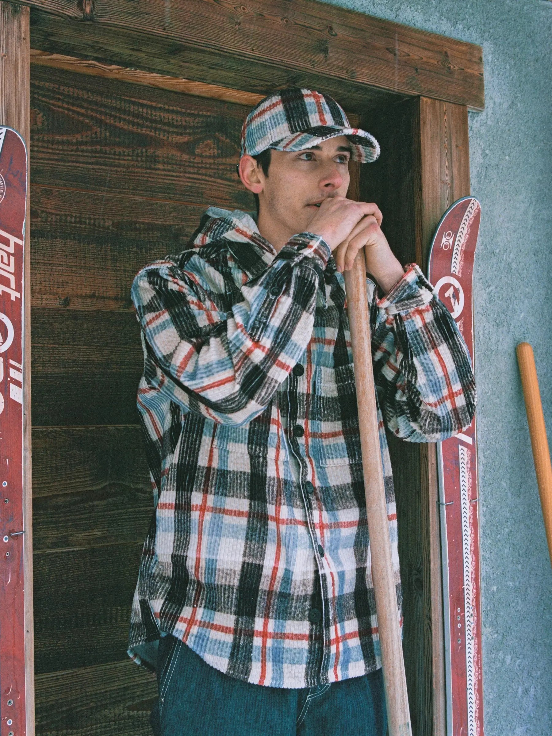 Stylish young man wearing multicolor plaid corduroy jacket with detachable hood outdoors
