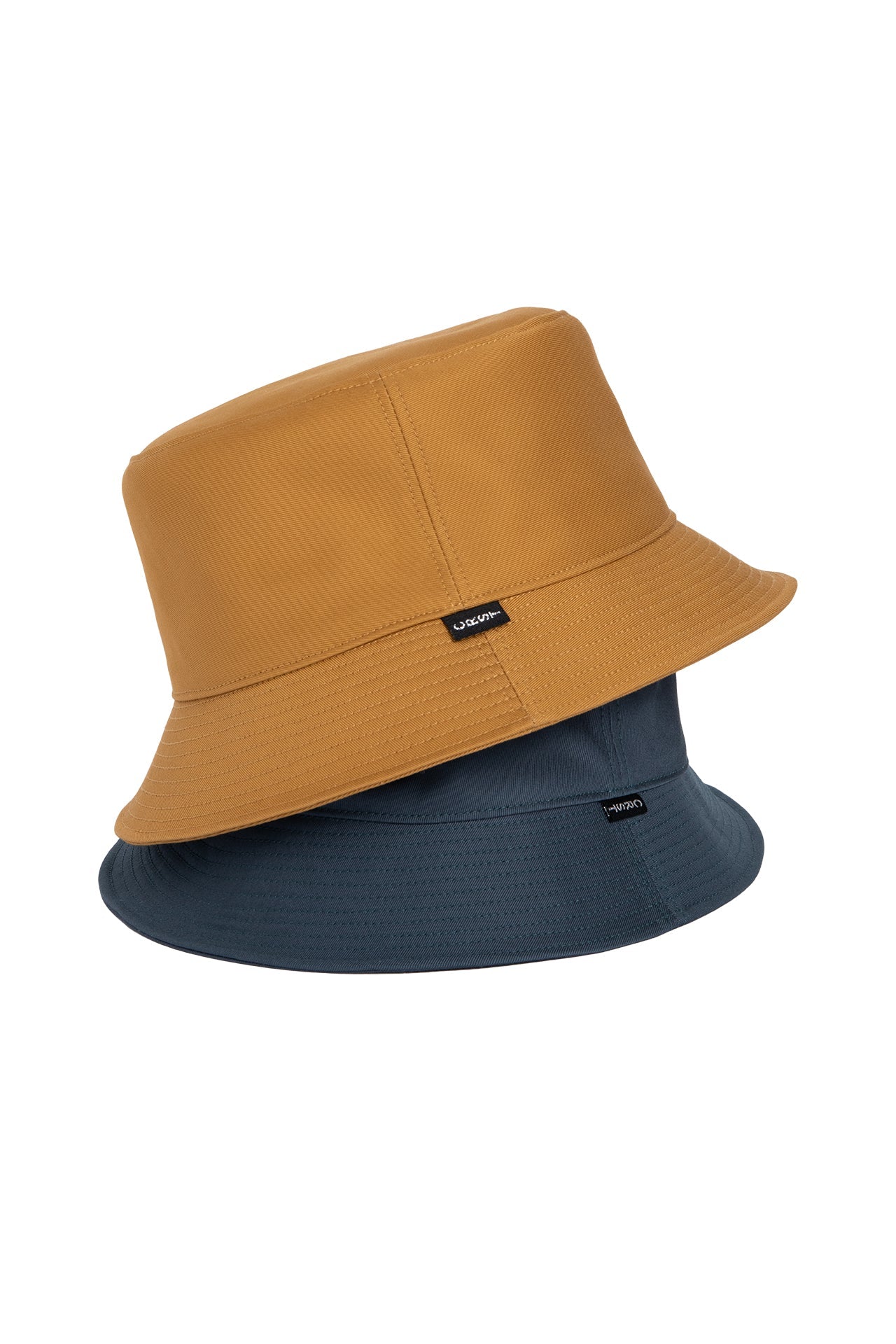 Two bucket hats in Mustard Yellow and Petrol Blue colors, showcasing Crest label. Crafted from premium Japanese Cotton Twill.