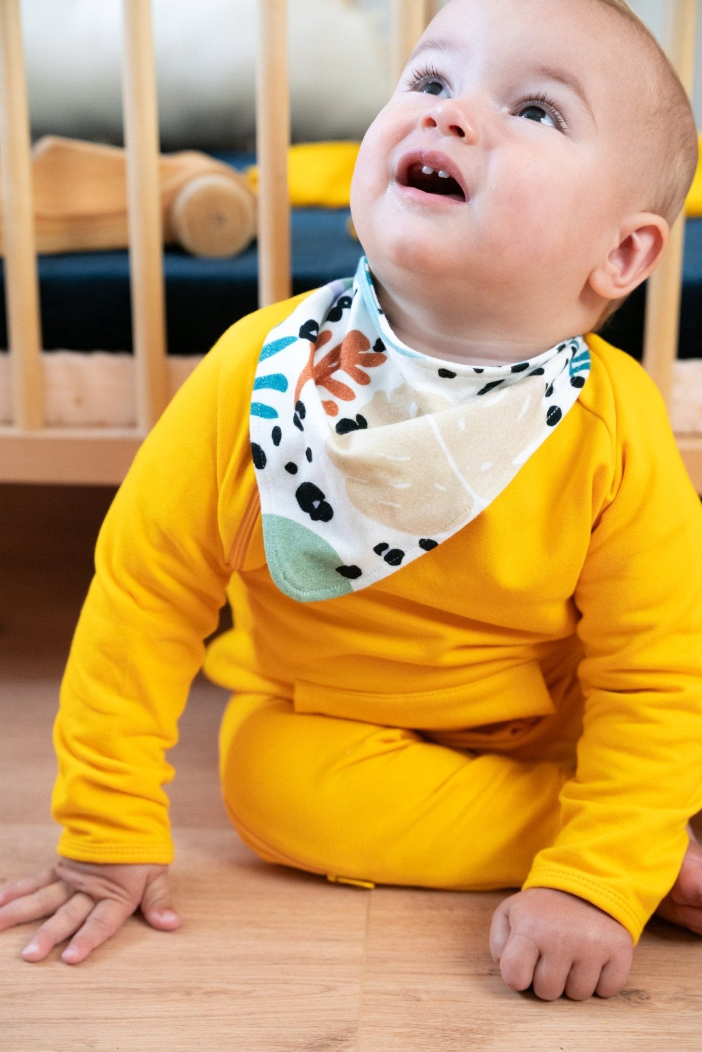 A baby wearing a bandana with tropical print by Swiss Brand Tilouco.