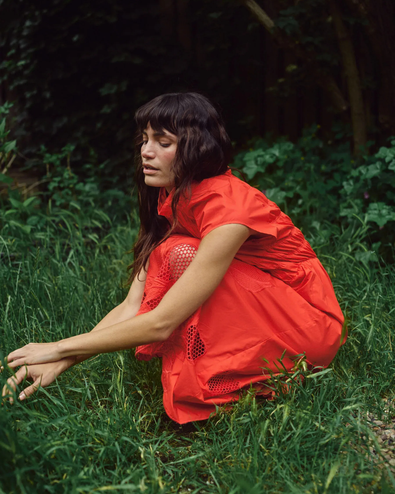 Model leaning wearing MMAria Mono Dress in Soft Coral, flowing midi-length skirt