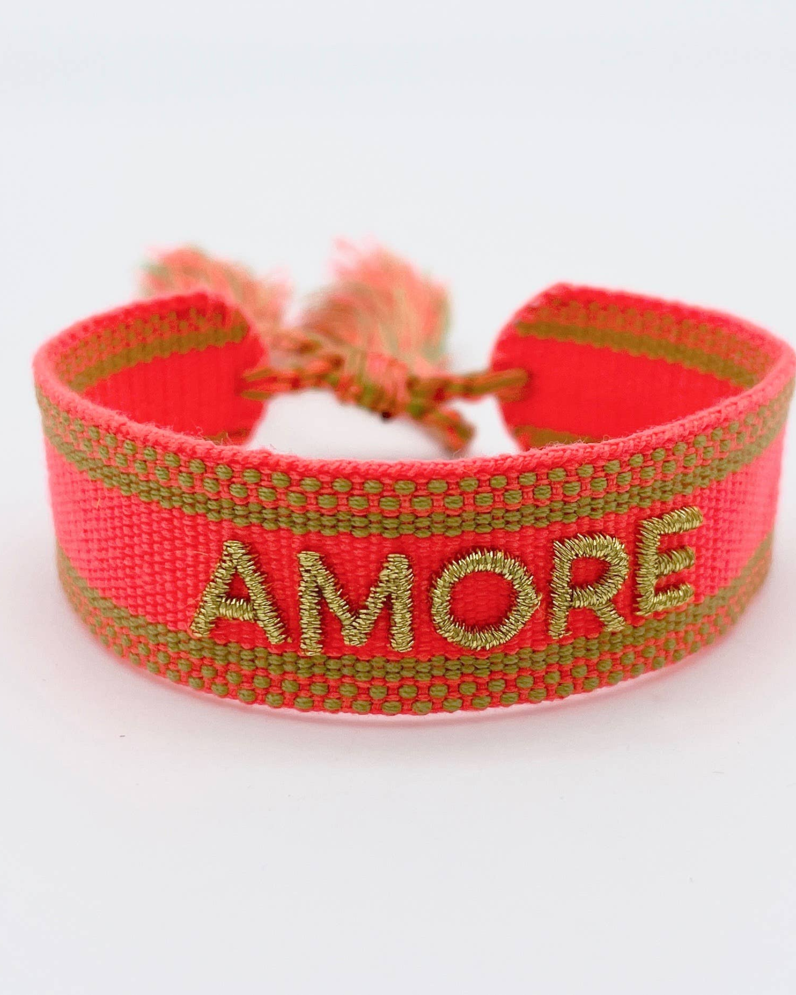 Close-up of adjustable neon orange woven friendship bracelet with green border and gold embroidered "AMORE" lettering and sliding knot cords.