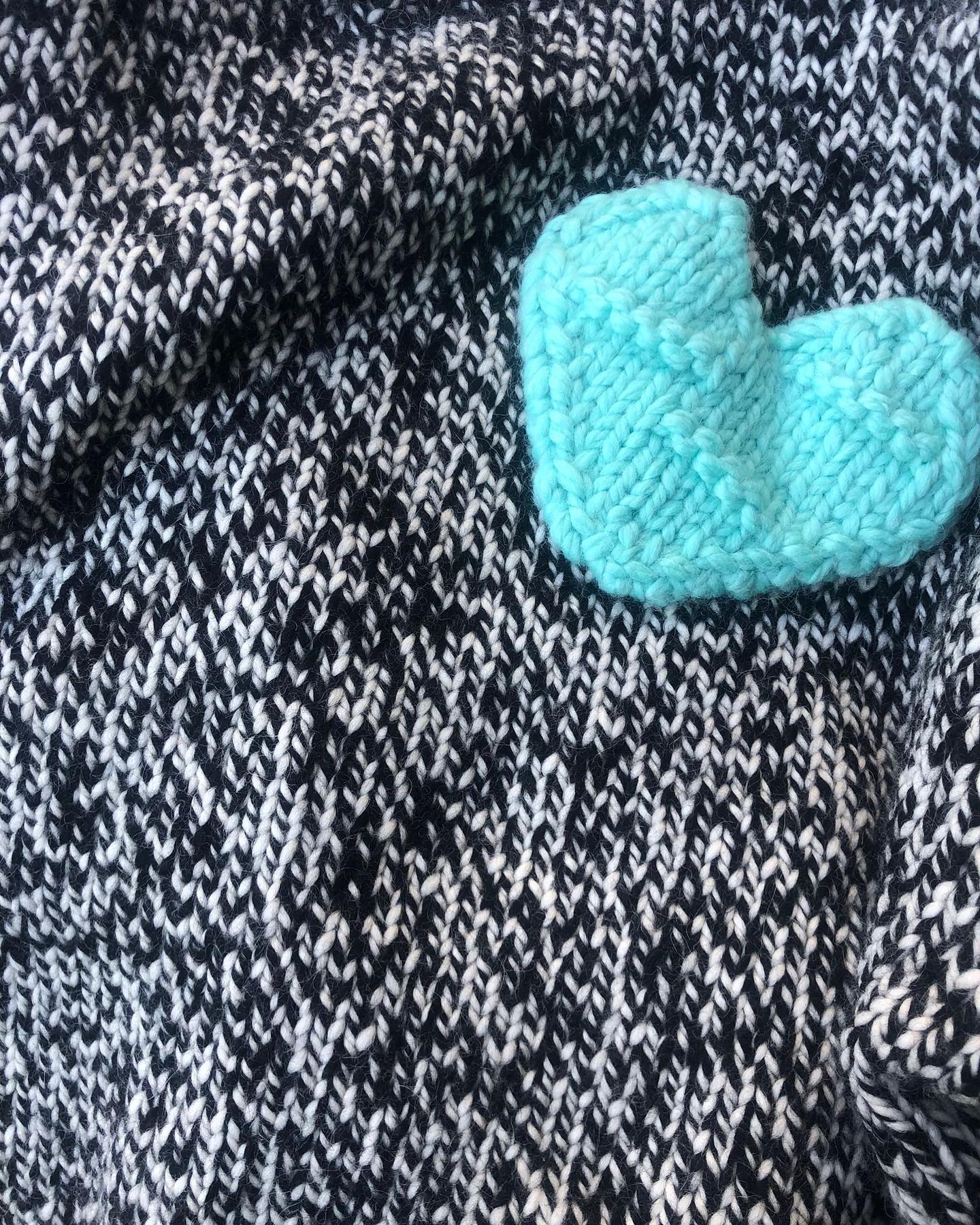 Handmade wool sweater in black and white melange with a bold turquoise heart – cozy, stylish, and artisan-crafted