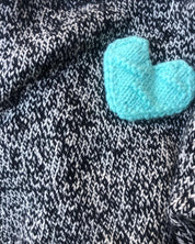 Handmade wool sweater in black and white melange with a bold turquoise heart – cozy, stylish, and artisan-crafted