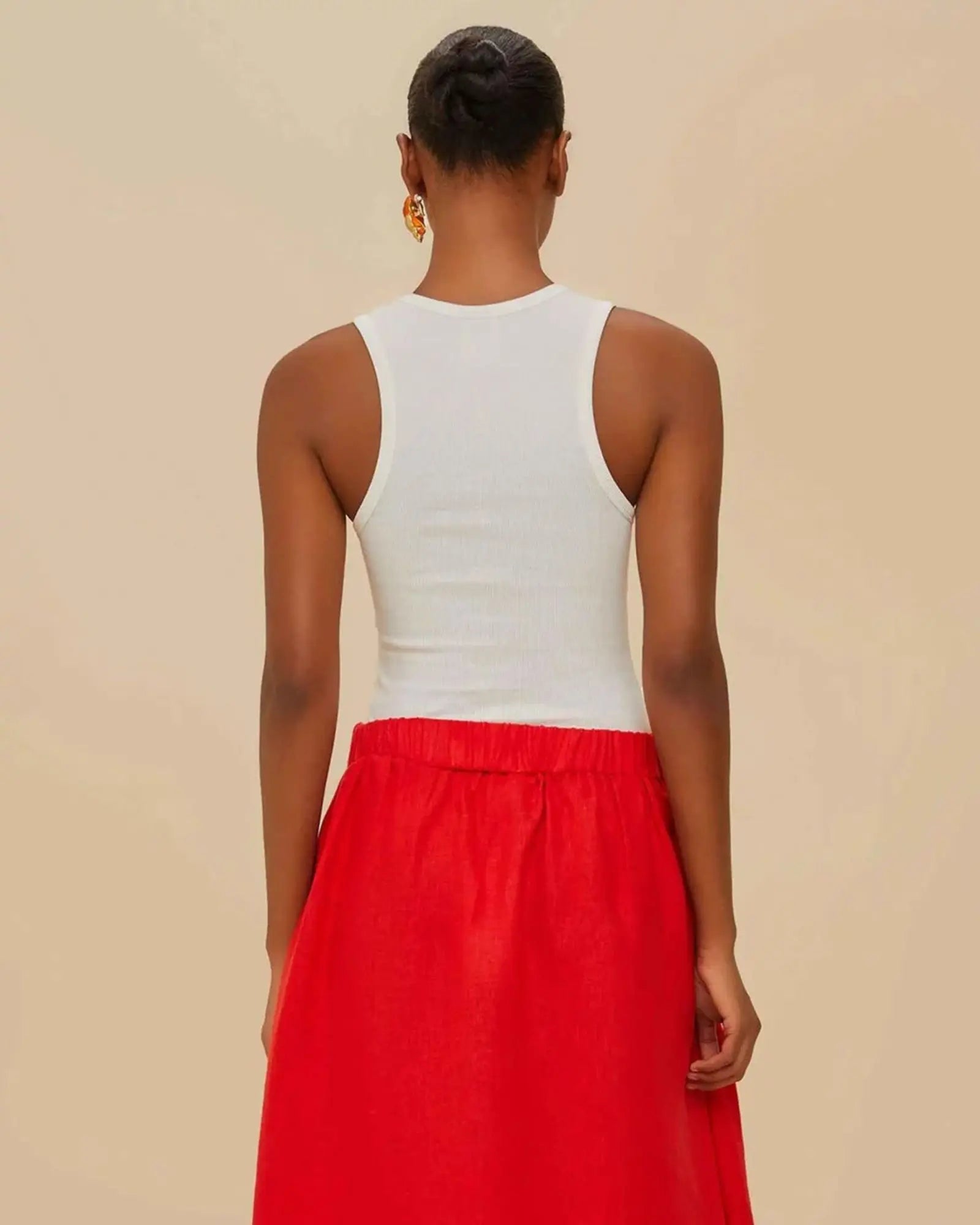 female model wearing the white ribbed Farm Rio tank top styled with a red skirt, showing the classic racerback cut at the back.