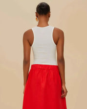 female model wearing the white ribbed Farm Rio tank top styled with a red skirt, showing the classic racerback cut at the back.