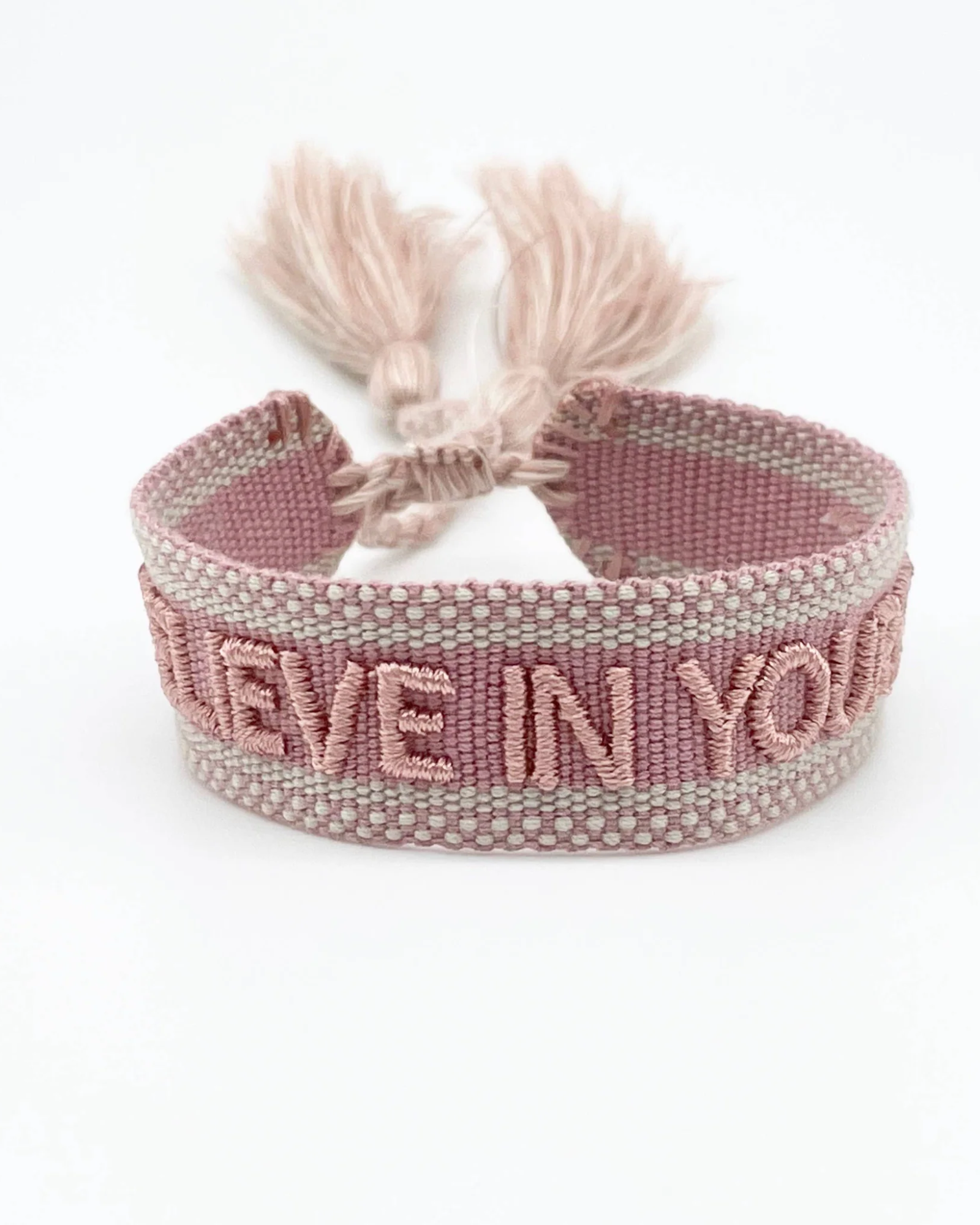 Close-up of adjustable vintage rose woven bracelet with embroidered “BELIEVE IN YOURSELF” lettering and sliding knot tassel cords.