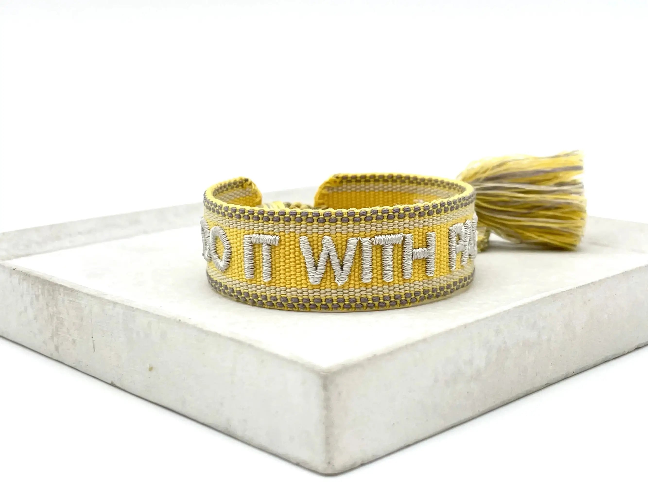 Close-up of adjustable woven friendship bracelet with silver phrase and tassels
