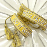 Two views of a bright yellow embroidered motivational quote bracelet on white ceramic.