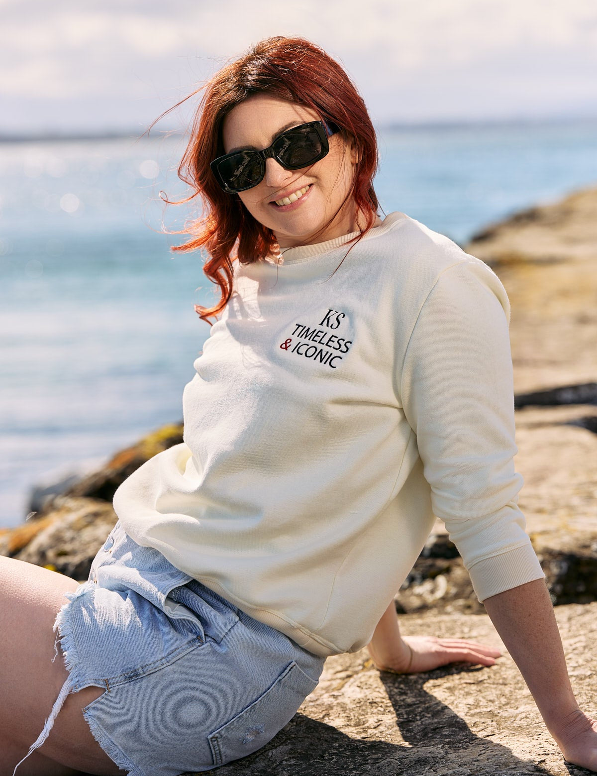 Woman wearing the Victoire Ecru Sweatshirt with a denim skirt and sunglasses.