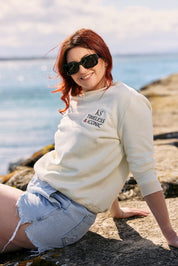 Woman wearing the Victoire Ecru Sweatshirt with a denim skirt and sunglasses.