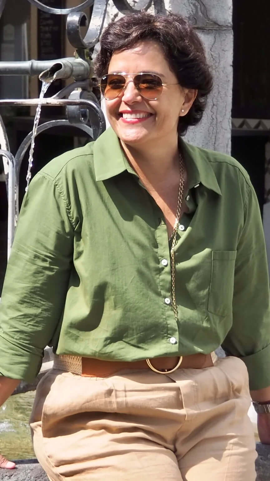 Woman in the city outside in the sunshine wearing the Khaki green Coachella Shirt in cotton voile by KS Vestiaire Intemporel