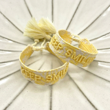 Close-up of adjustable yellow sorbet woven bracelet with embroidered “KEEP SMILING” lettering and sliding knot tassel cords.
