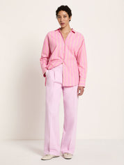 Model wearing bright orchid striped shirt with wide-leg pink trousers, full length