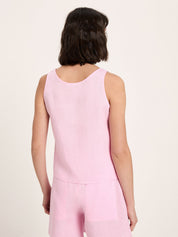 Person wearing a pink sleeveless top and pants on a light pink background