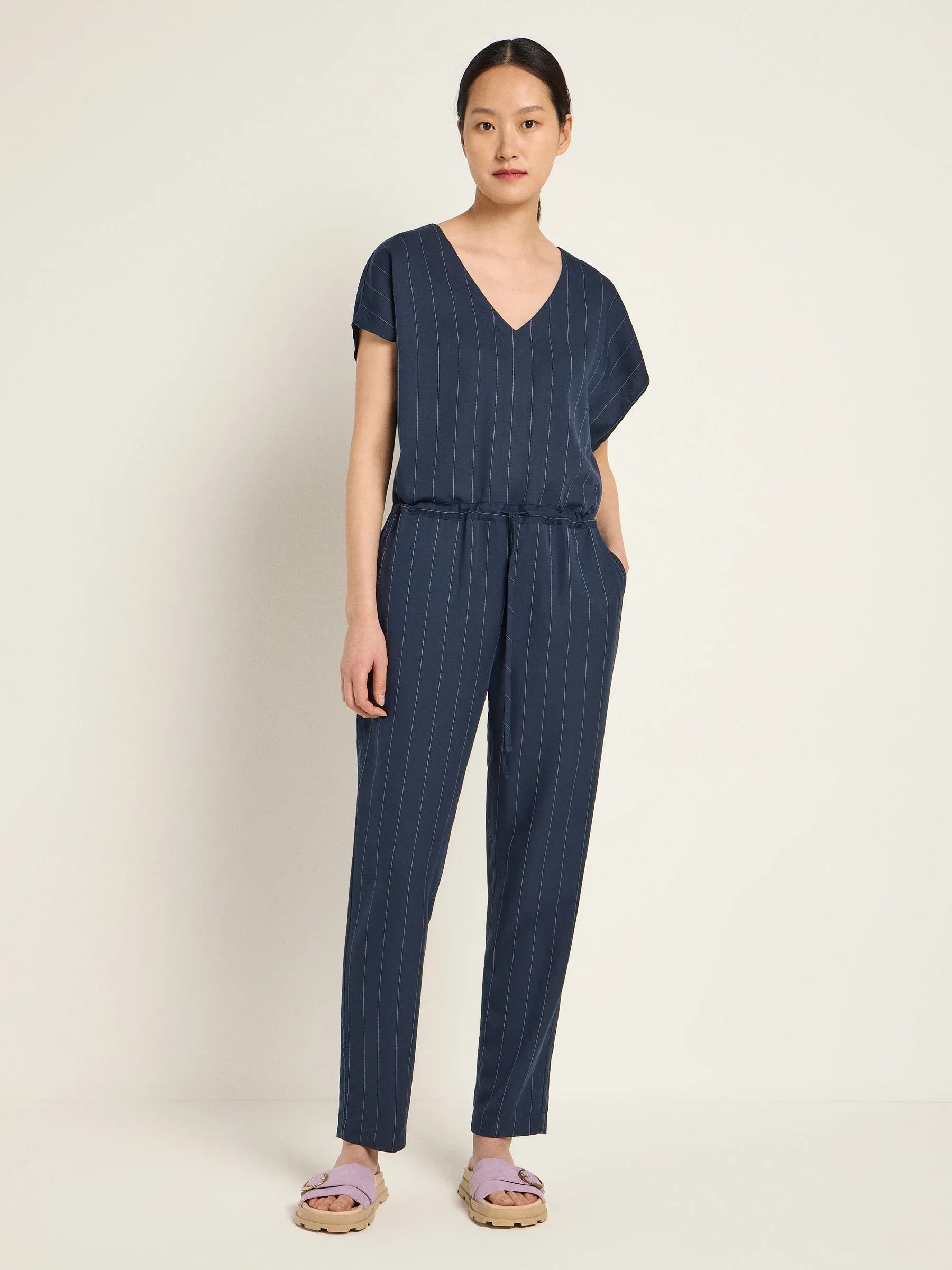 Woman wearing a navy blue striped jumpsuit by Lanius Fair Fashion - office essentials