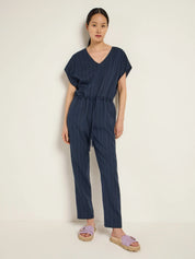 Woman wearing a navy pinstripe jumpsuit in a photo studio.