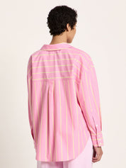 Back view of oversized pink striped shirt on model, box pleat and yoke detail visible.
