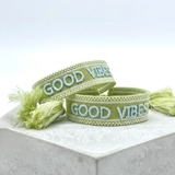 Close-up of adjustable cornflower blue woven bracelet with embroidered “LIVE LOVE SHINE” lettering and sliding knot tassel cords.