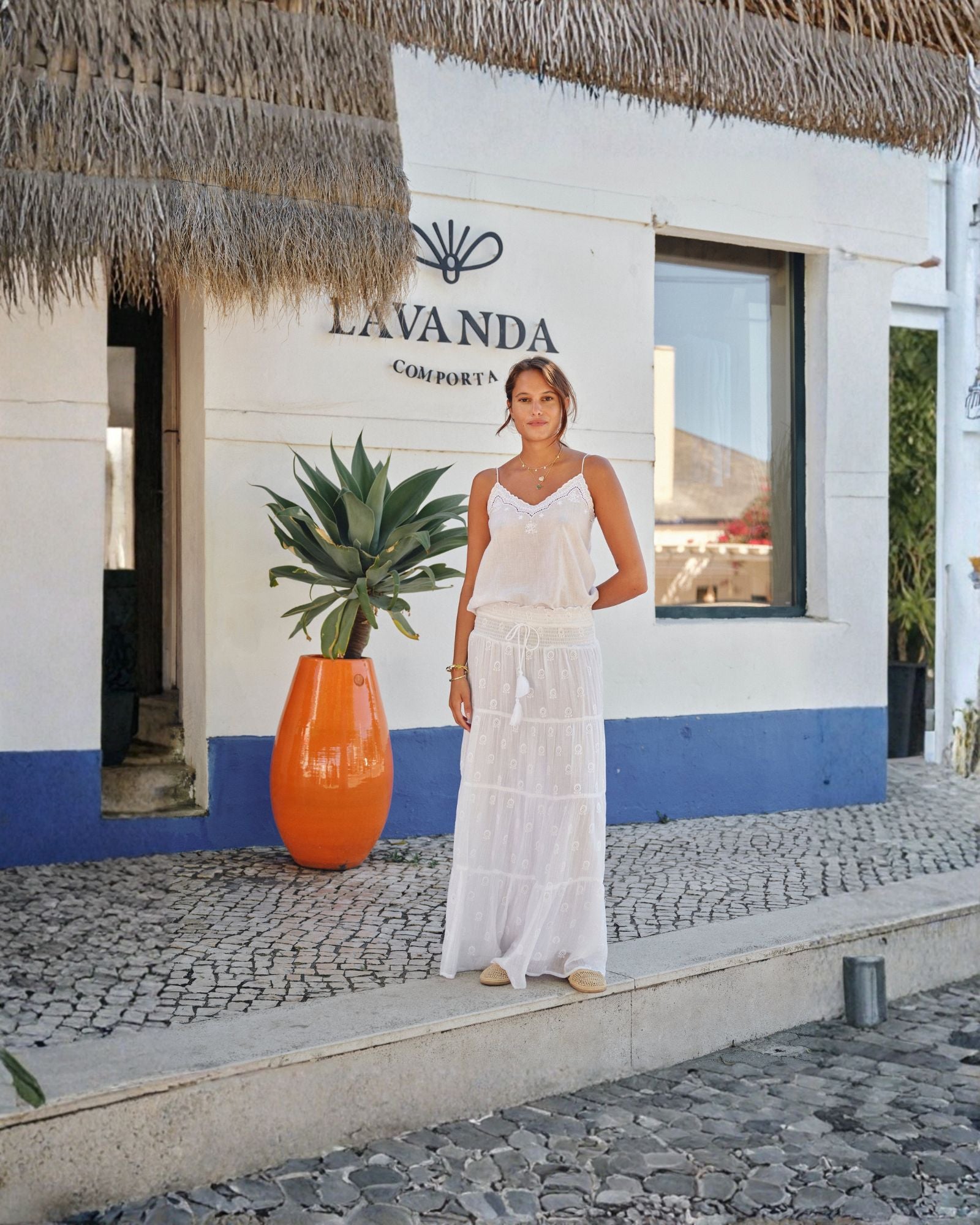 Model wearing white embroidered camisole styled with long skirt