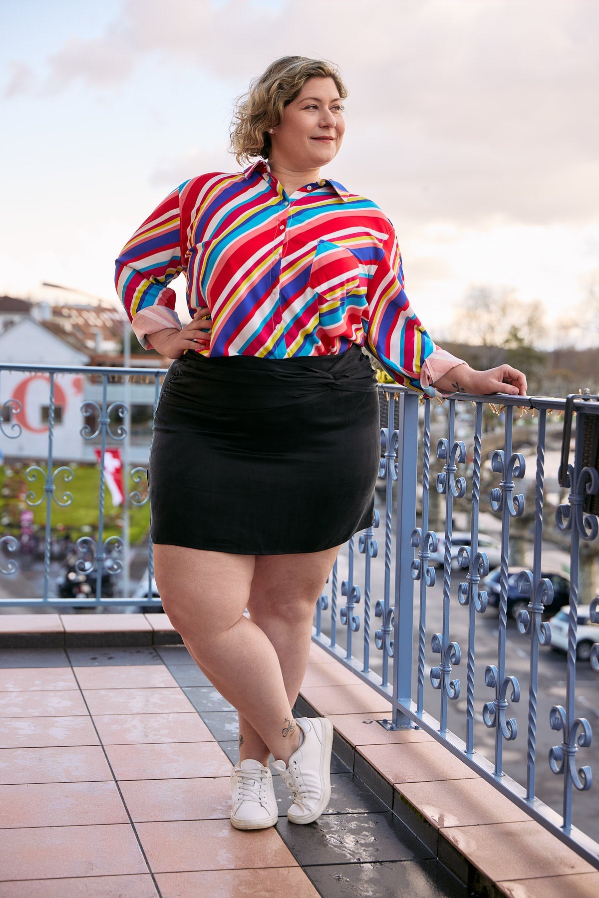A plus-size woman stands confidently wearing a sleek black cupro mini skirt.