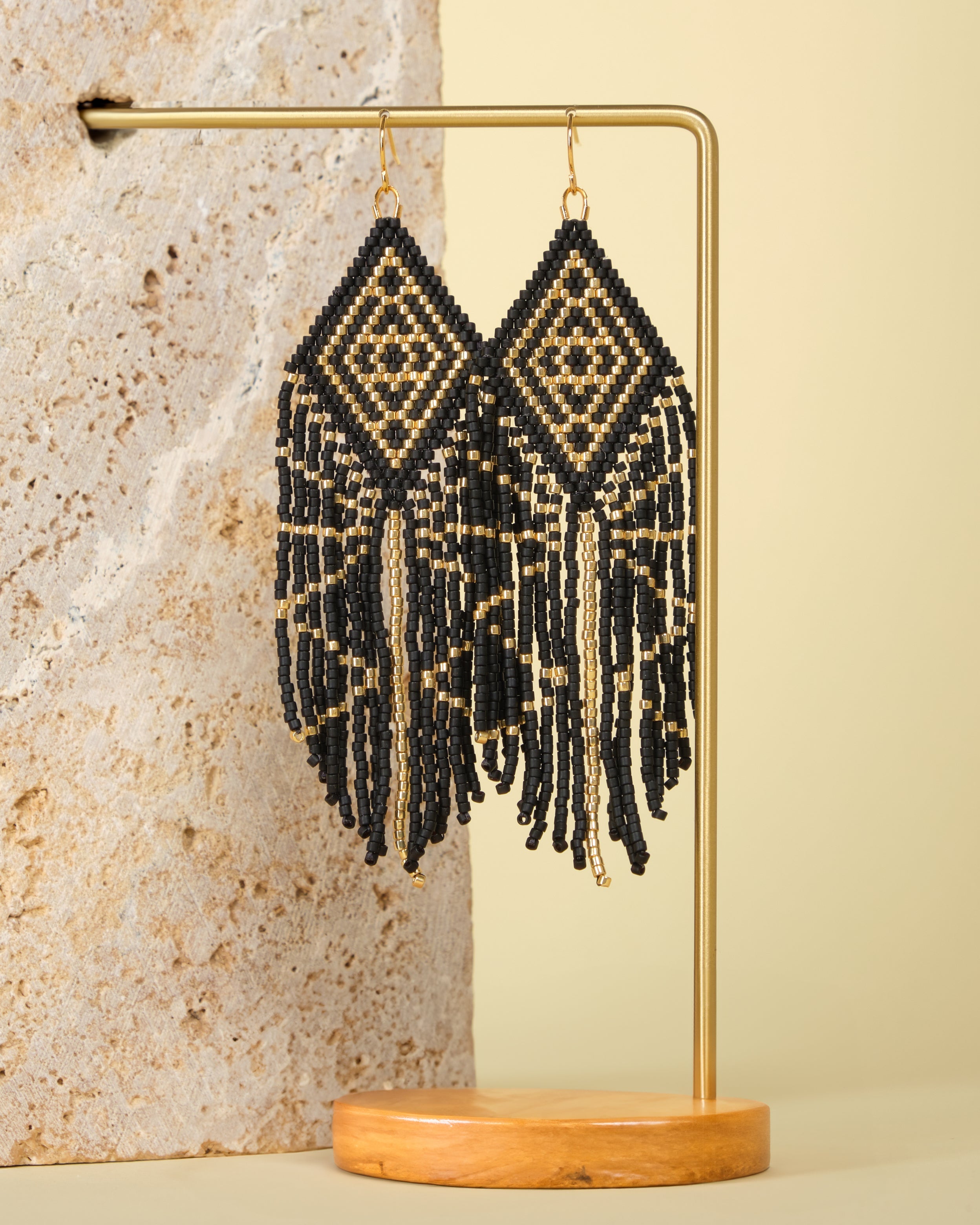 Gold – Elegant beaded earrings displayed on a textured jewelry stand