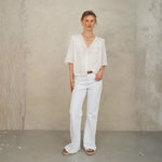 Model wearing white lace cotton blouse by Mabe Apparel with lace trim and V-necklin