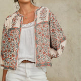 Detailed view of the collarless neckline and billowy sleeves on a Mabe Apparel floral print cotton jacket.