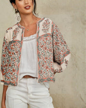 Detailed view of the collarless neckline and billowy sleeves on a Mabe Apparel floral print cotton jacket.