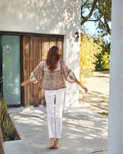 Model wearing Della jacket walking outside a modern house with a wooden door.