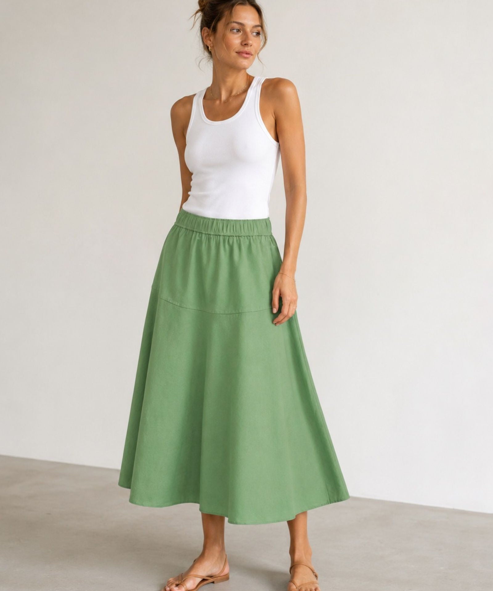 Woman wearing Mos Mosh MMEllaja sage green A-line midi skirt, styled with white tank top