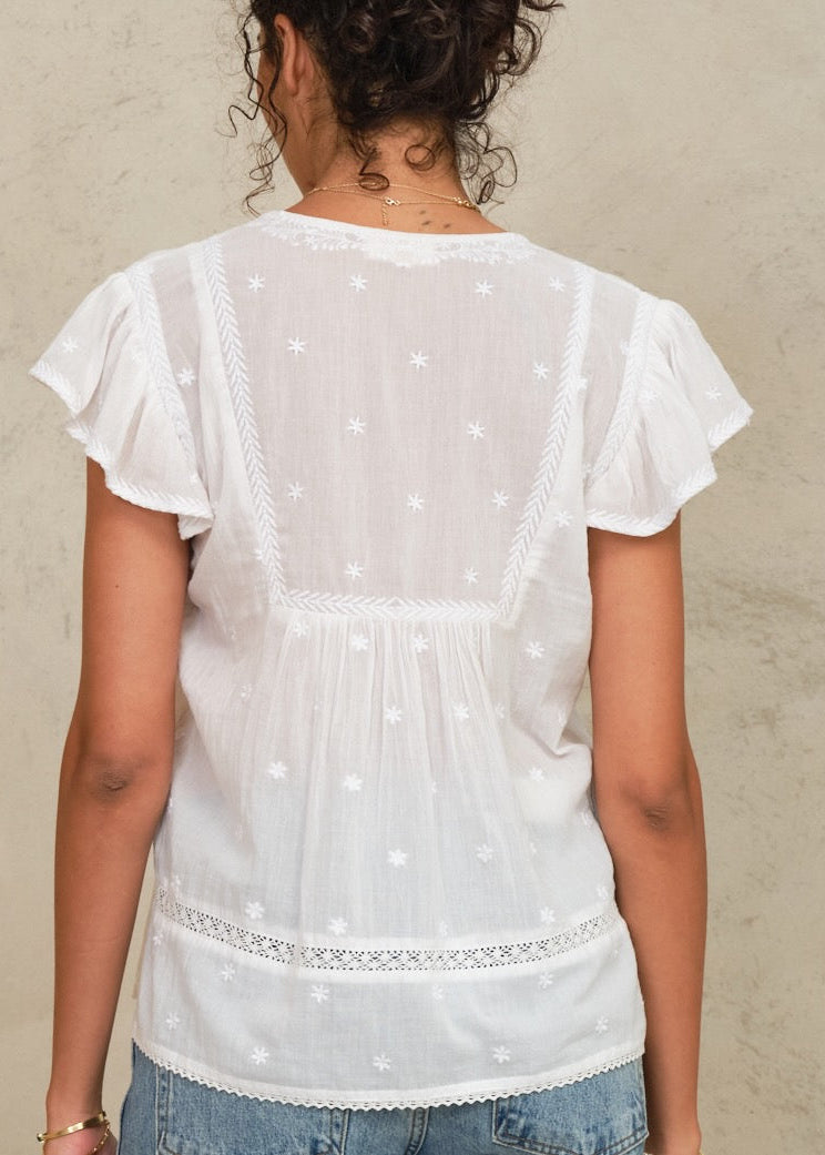 White embroidered Navi top worn by a person against a neutral background