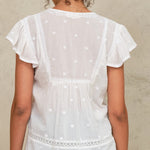 White embroidered Navi top worn by a person against a neutral background