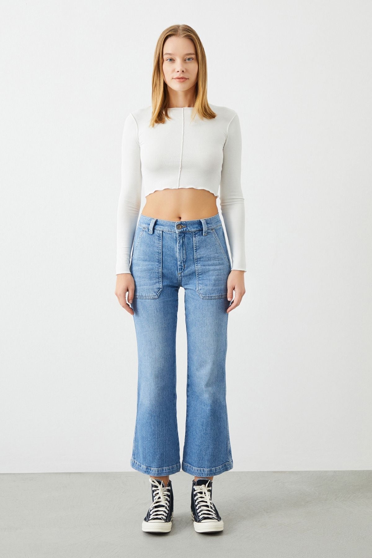 Model wearing Leyl Crop Flare Fit Jeans with white crop top by Sustainable Denim Brand Ra Denim, showcasing their trendy and flattering silhouette.