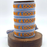Close-up of adjustable blue and orange woven friendship bracelet featuring embroidered "SUNSHINE & GOOD VIBES" lettering and sliding knot tassel cords.