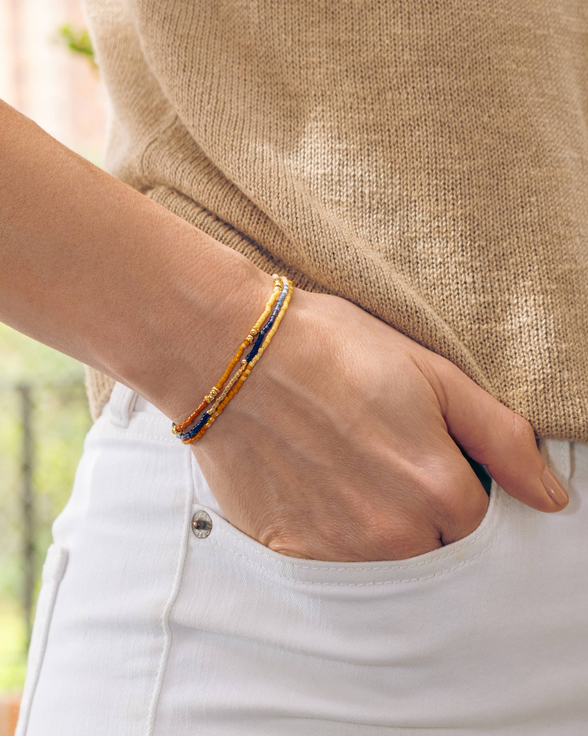 Woman wears Miyuki Beaded Stretch Bracelet Trio in Peach Aqua Tan – a colorful, elegant bracelet set.