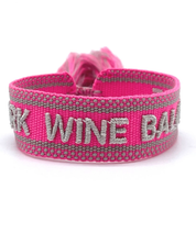 Close-up of adjustable pink woven bracelet with silver gray embroidered “WORK WINE BALANCE” lettering, matching border, and sliding knot tassel cords.