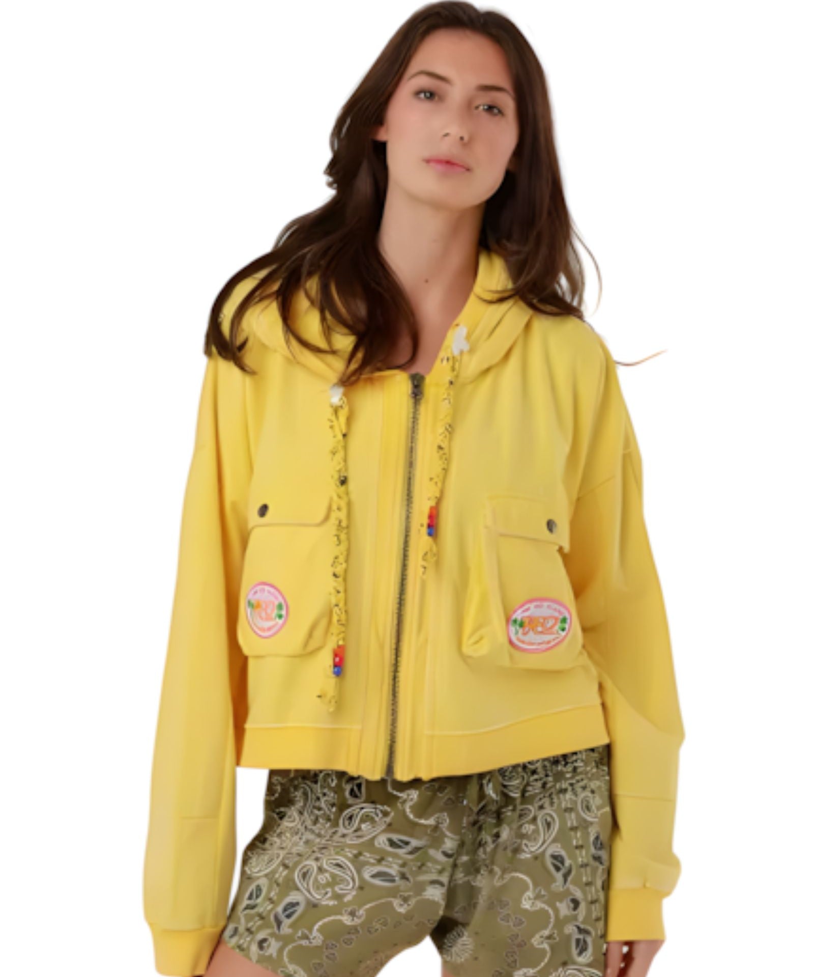 A woman wearing the vibrant yellow Amy cotton zip-up hooded jacket with cargo chest pockets and colorful beaded drawstring details.
