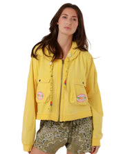A woman wearing the vibrant yellow Amy cotton zip-up hooded jacket with cargo chest pockets and colorful beaded drawstring details.