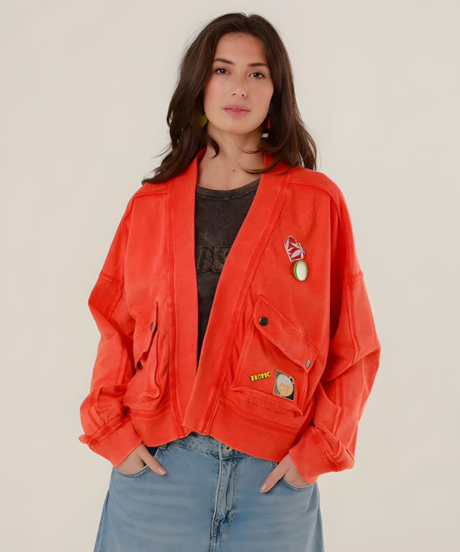 A woman facing forward wearing the oversized red acid-washed Azellia cotton jacket with large utility pockets and decorative front patches.