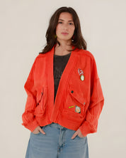 A woman facing forward wearing the oversized red acid-washed Azellia cotton jacket with large utility pockets and decorative front patches.