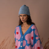 COLORUSH Byron cashmere beanie in Stonewash, worn from the front with a pink and blue cardigan