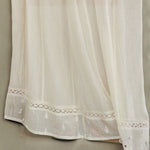 Detailed close-up of the openwork crochet lace and delicate embroidery on a cream Mabe Apparel skirt.
