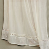 Detailed close-up of the openwork crochet lace and delicate embroidery on a cream Mabe Apparel skirt.