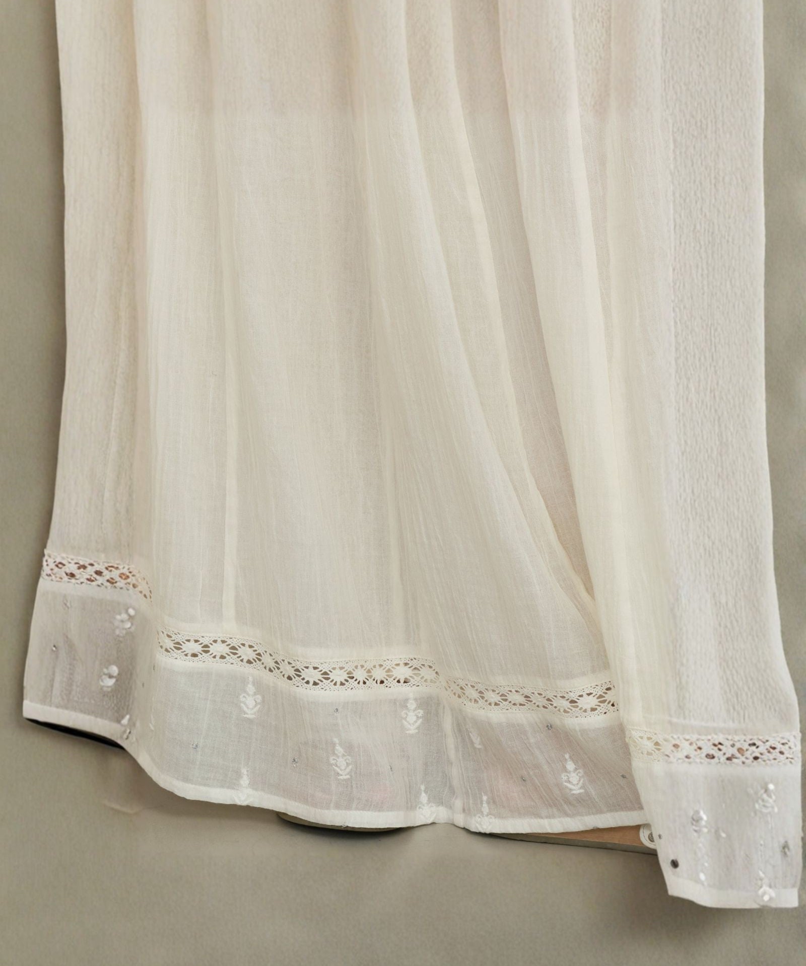 Detailed close-up of the openwork crochet lace and delicate embroidery on a cream Mabe Apparel skirt.