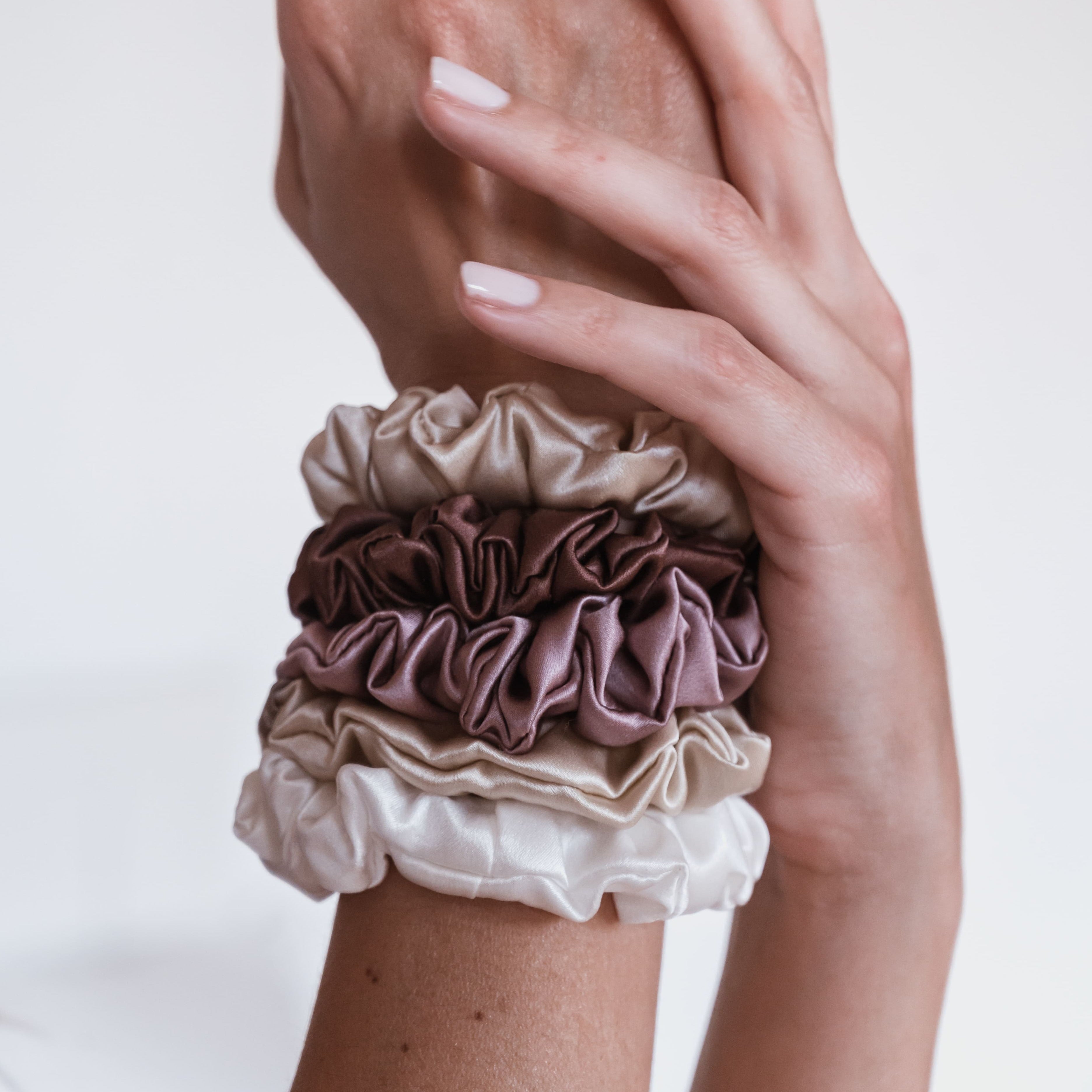 Emily's Pillow silk scrunchies in champagne, mocha and ivory worn stacked on the wrist