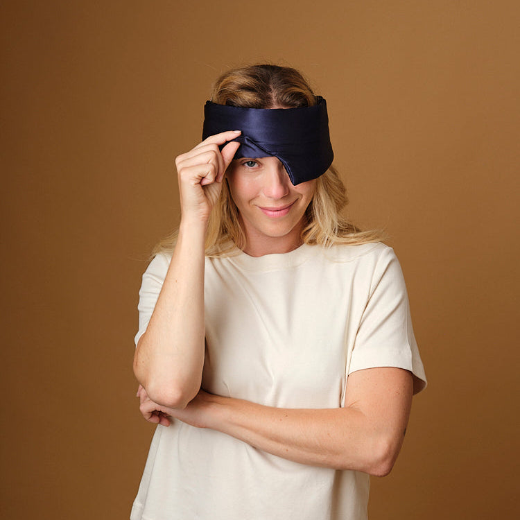 Woman wearing the Emily's Pillow pure silk headband sleep mask in midnight blue