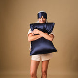 Woman in pyjamas with the Emily's Pillow midnight blue silk sleep mask